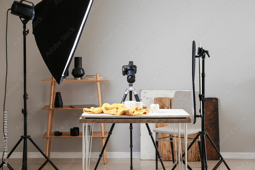 Interior of modern photo studio with professional equipment and drink on table