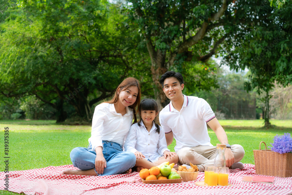 Asian teen family happy holiday picnic moment in the park with father, mother and daughter looking a