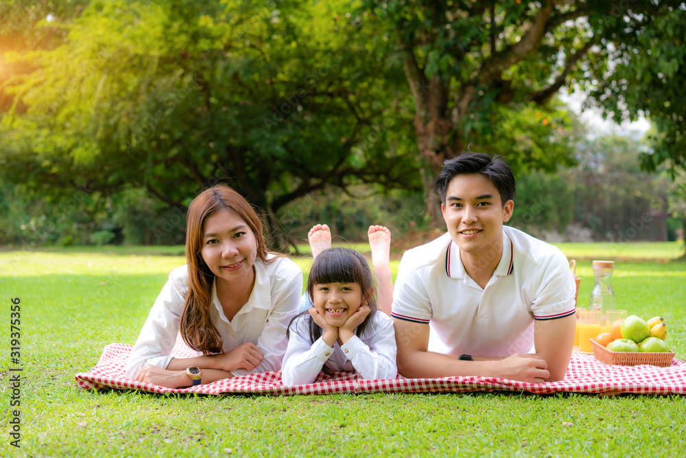 Asian teen family happy holiday picnic moment in the park with father, mother and daughter lying on 