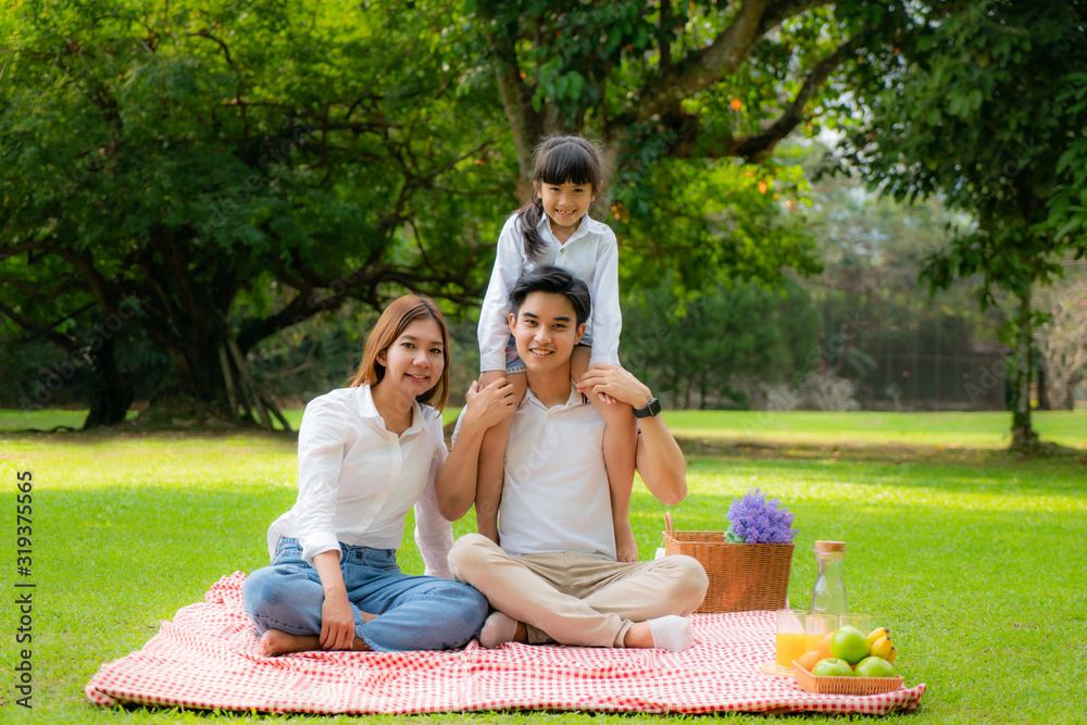 Asian teen family happy holiday picnic moment in the park with father, mother and daughter looking a