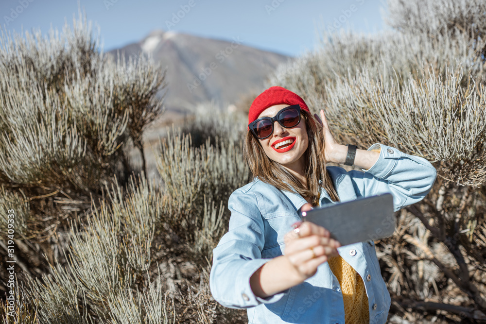 Young woman photographing or vlogging on phone during her travel on the volcano valley. Lifestyle tr