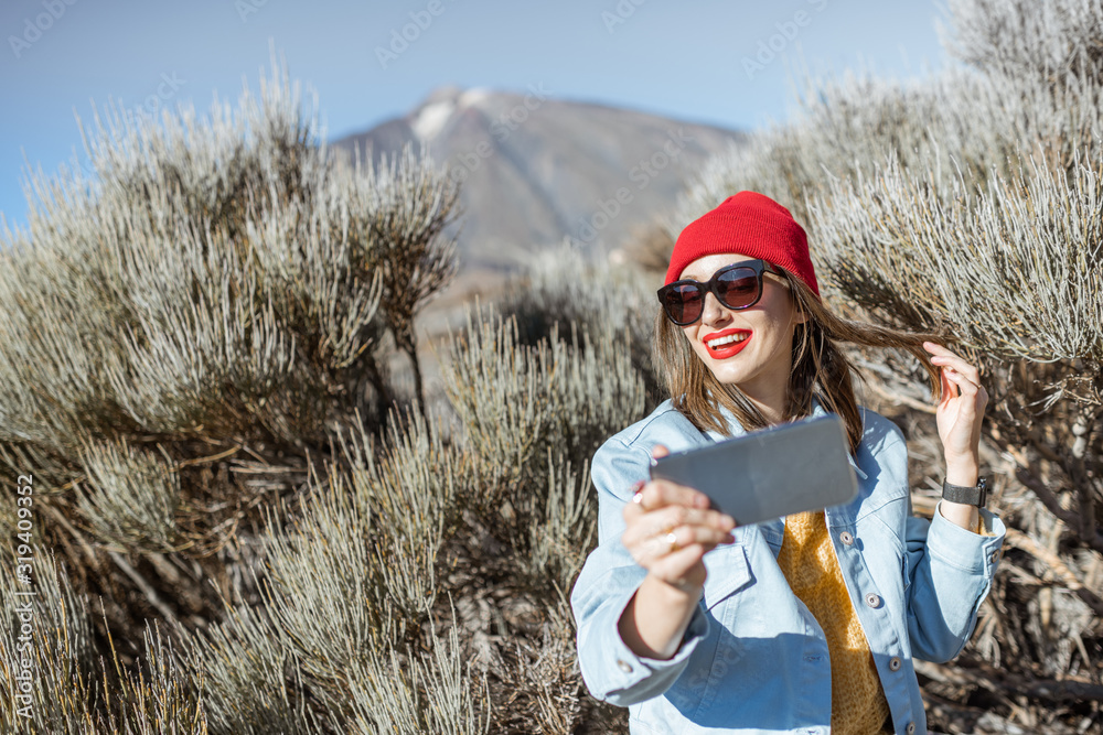 Young woman photographing or vlogging on phone during her travel on the volcano valley. Lifestyle tr