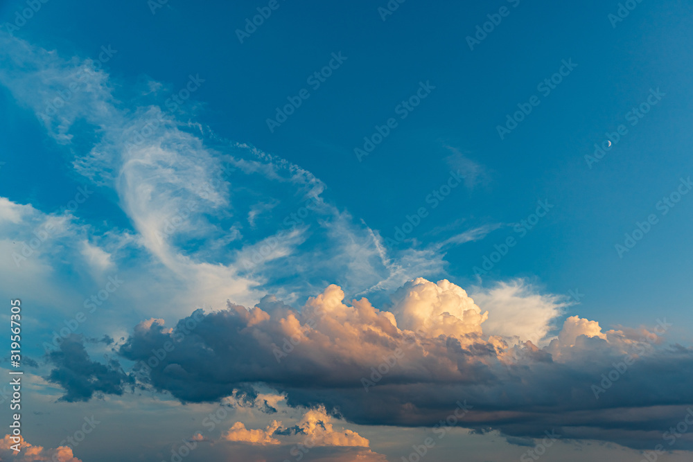 白色、橙色和深色的云层，日落的夏季背景是蓝天