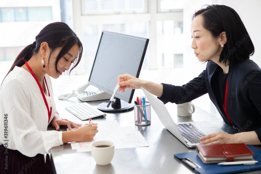 資料を確認し合う女性社員たち