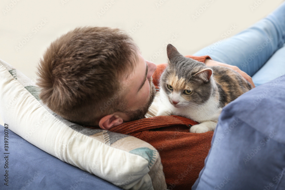 家里沙发上躺着一只可爱猫咪的男人