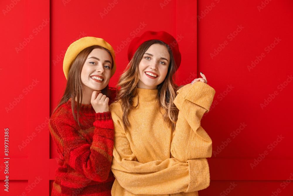 Young women in warm sweaters on color background