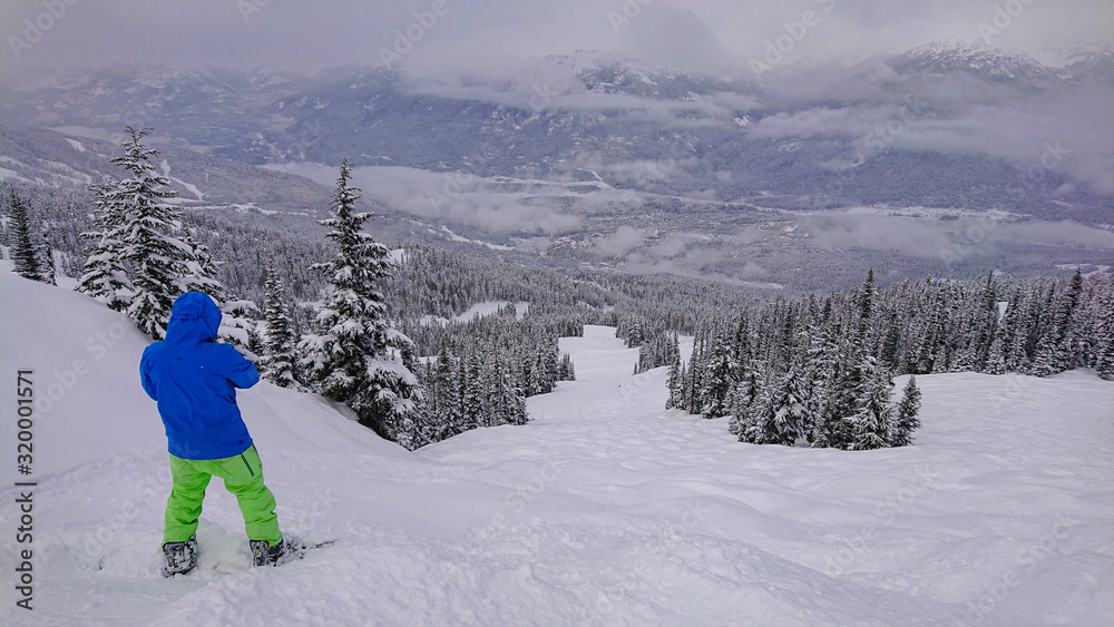 COPY SPACE: Snowboarder takes photos of landscape before riding down mountain.