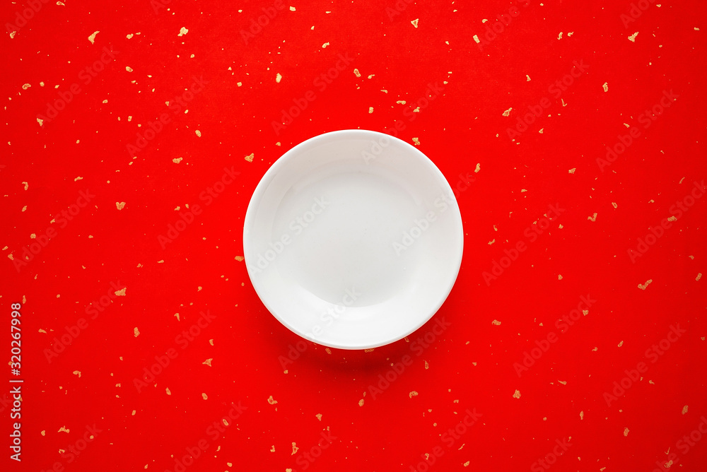 A white ceramic empty plate on a red background