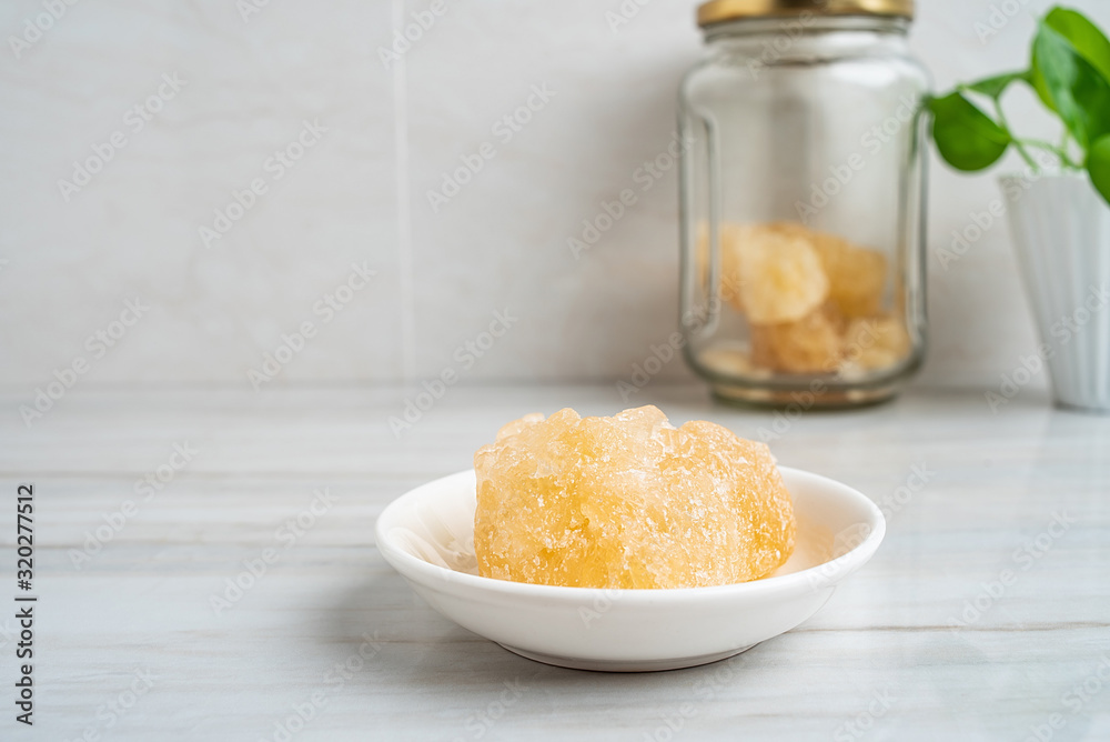 A dish of yellow rock sugar on the kitchen tile countertop