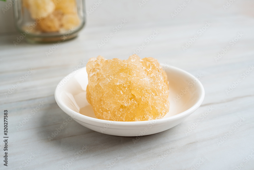 A dish of yellow rock sugar on the kitchen tile countertop