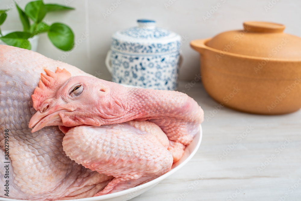 Soup casserole and fresh hen on a kitchen tile countertop