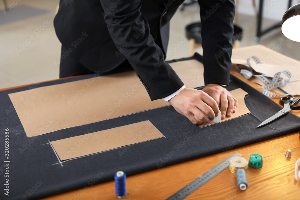 Young tailor working at table in atelier