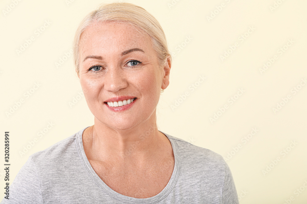 Beautiful mature woman with healthy skin on color background