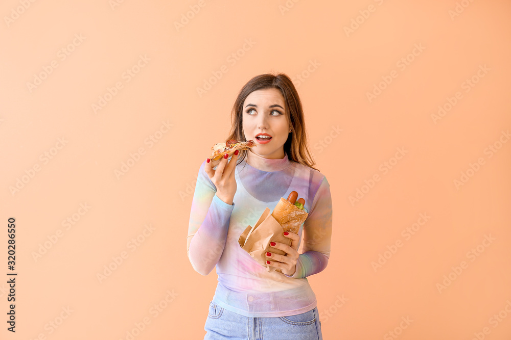 Portrait of beautiful young woman with French hot dog and pizza on color background