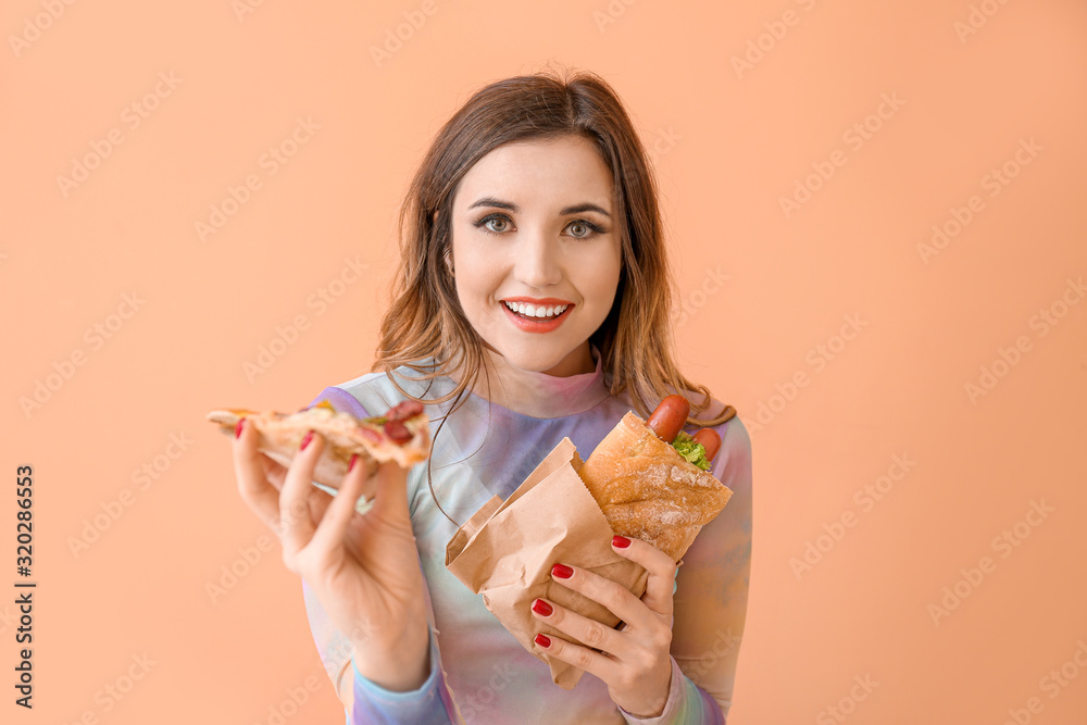 Portrait of beautiful young woman with French hot dog and pizza on color background