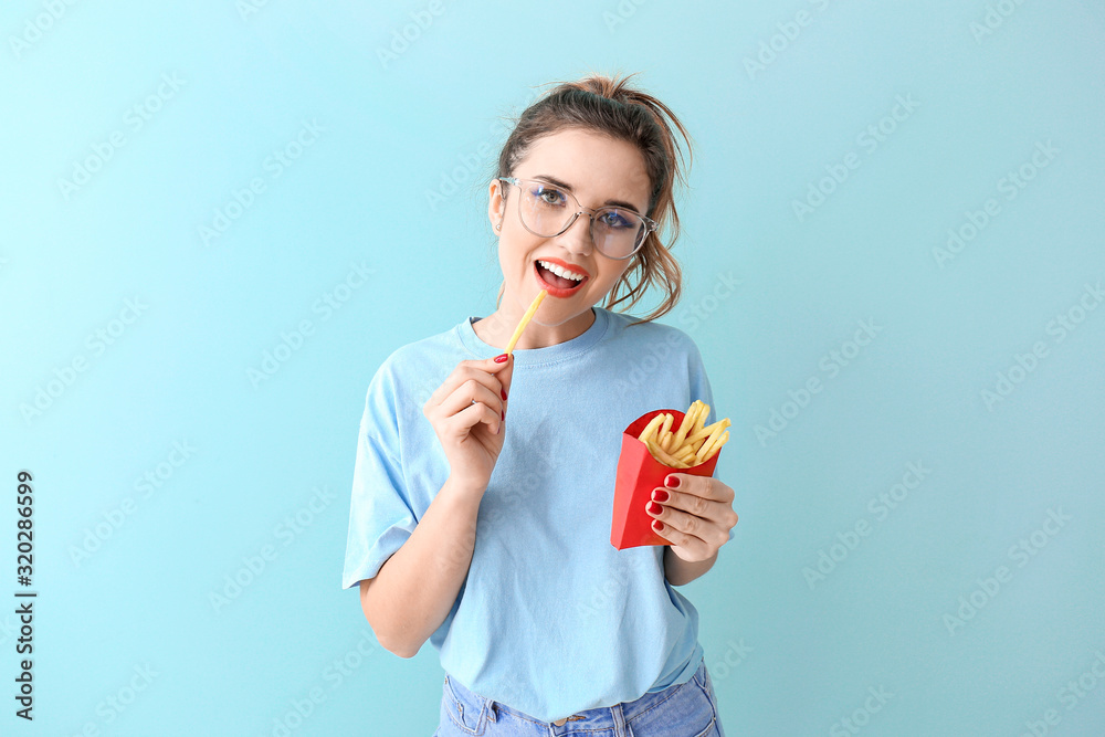 Portrait of beautiful young woman with french fries on color background