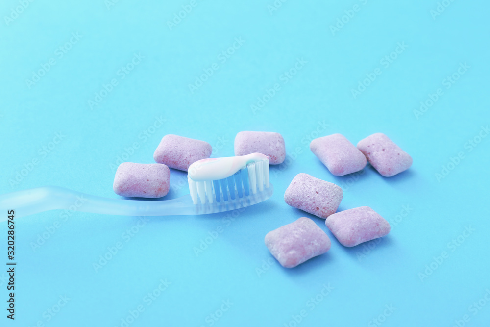 Tooth brush with paste and chewing gums on color background