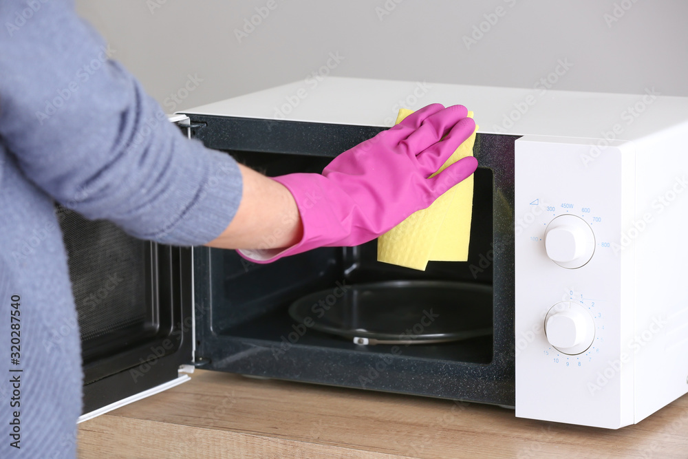 Woman cleaning microwave oven in kitchen