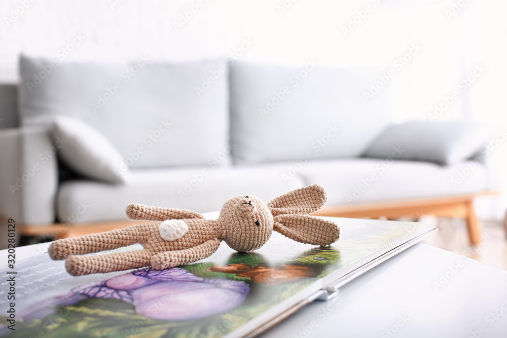 Cute baby toy and book on table