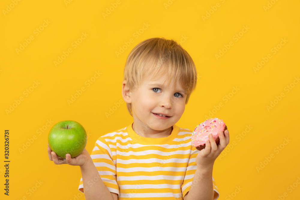 Happy child holding donut and apple