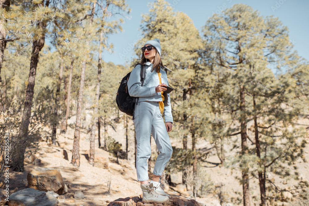 Portrait od a stylish woman enjoying beautiful landscapes on volcanic rocks in the pine woods, trave