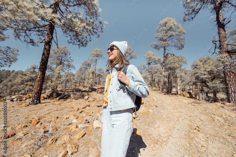 年轻女子穿着休闲，背着背包在火山上高山的森林中行走