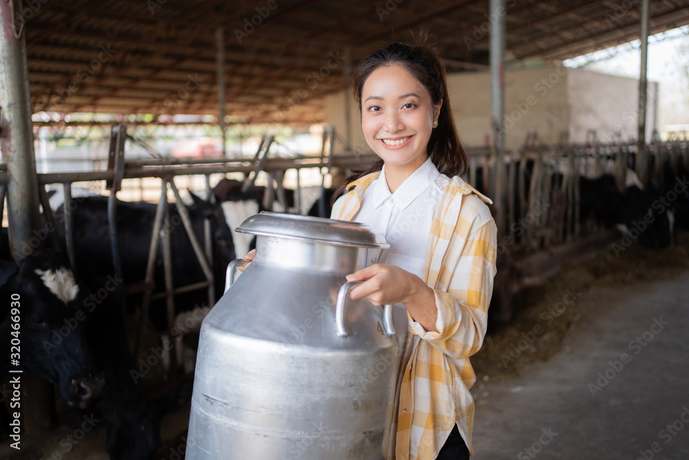 肖像农民，一位亚洲妇女在他的农场里拿着一容器牛奶。