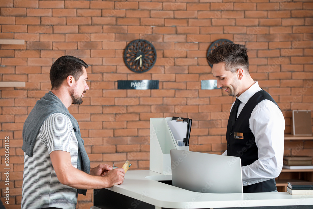 Man booking room in hotel at reception