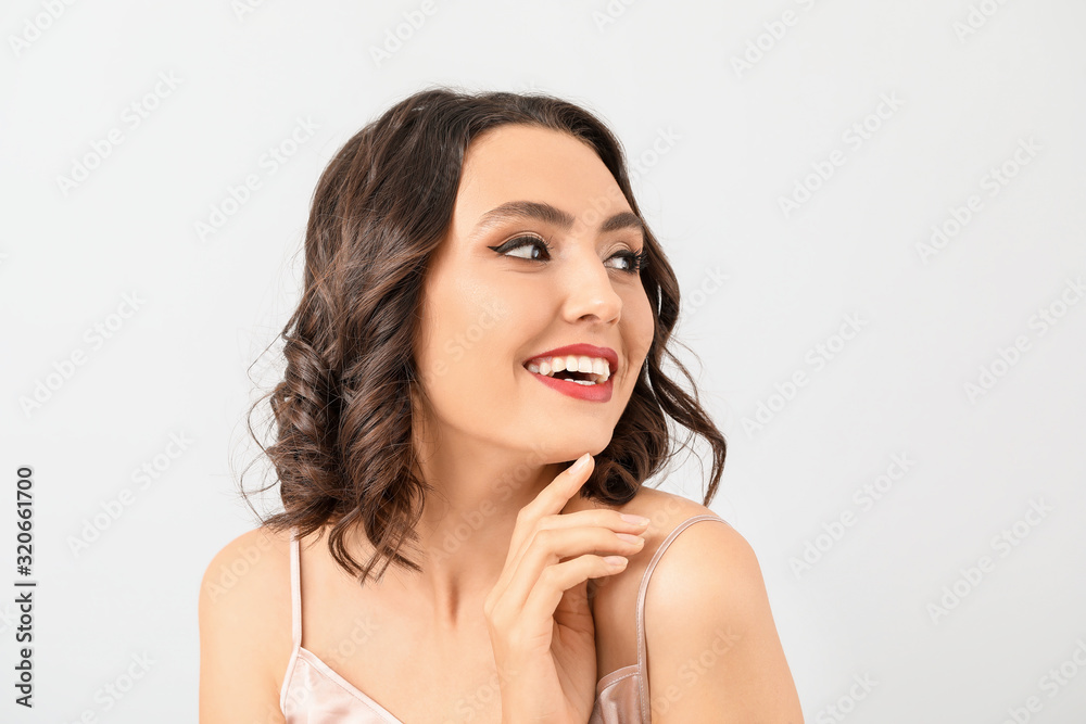 Beautiful young woman with stylish makeup on light background