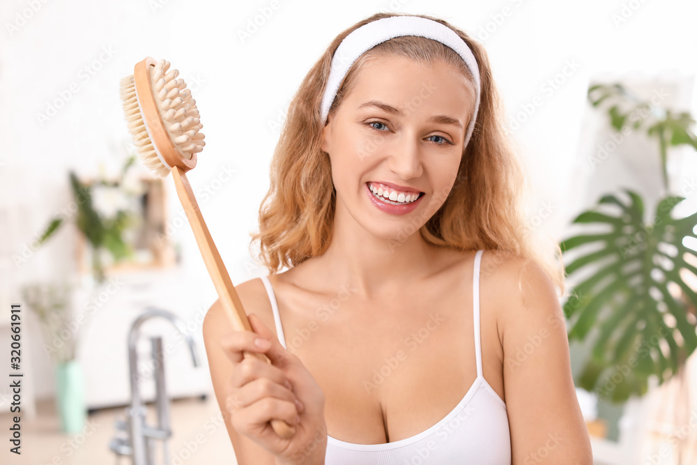 Beautiful young woman with massage brush in bathroom