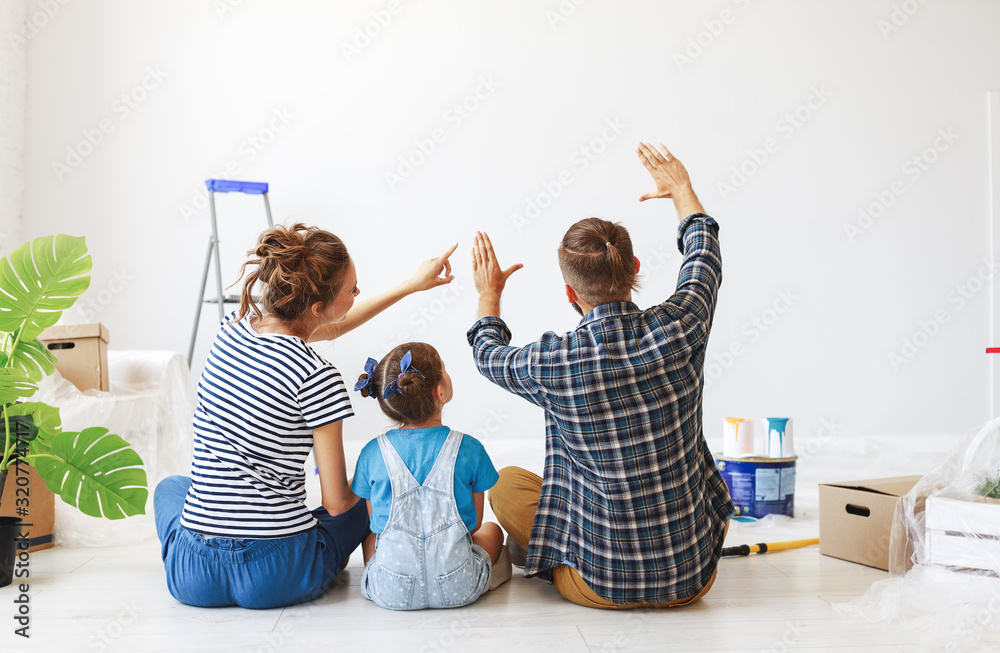 Repair in apartment. Happy family mother, father and child daughter  paints wall