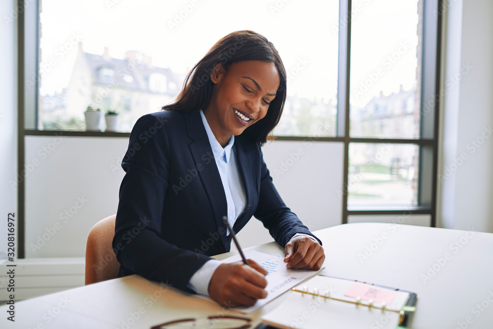 Smiling African American businesswoman writing notes at an offic