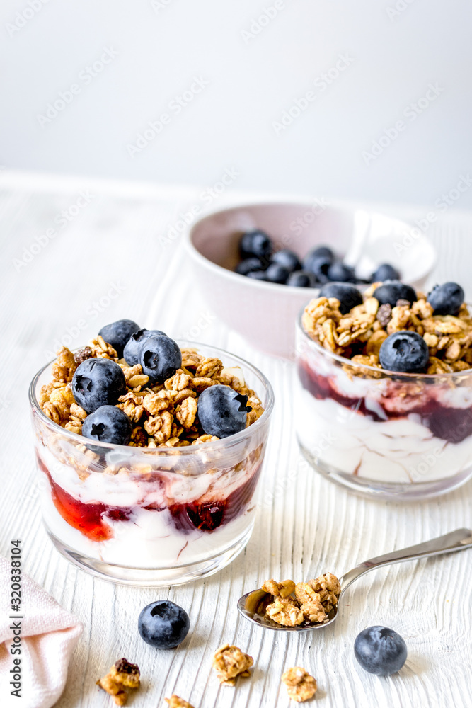 Cooking breakfast with granola and berries on white kitchen background