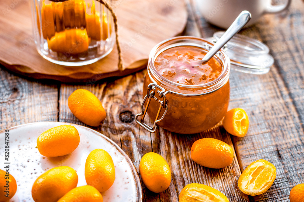 kumquat on plate and jam in jar at wooden table