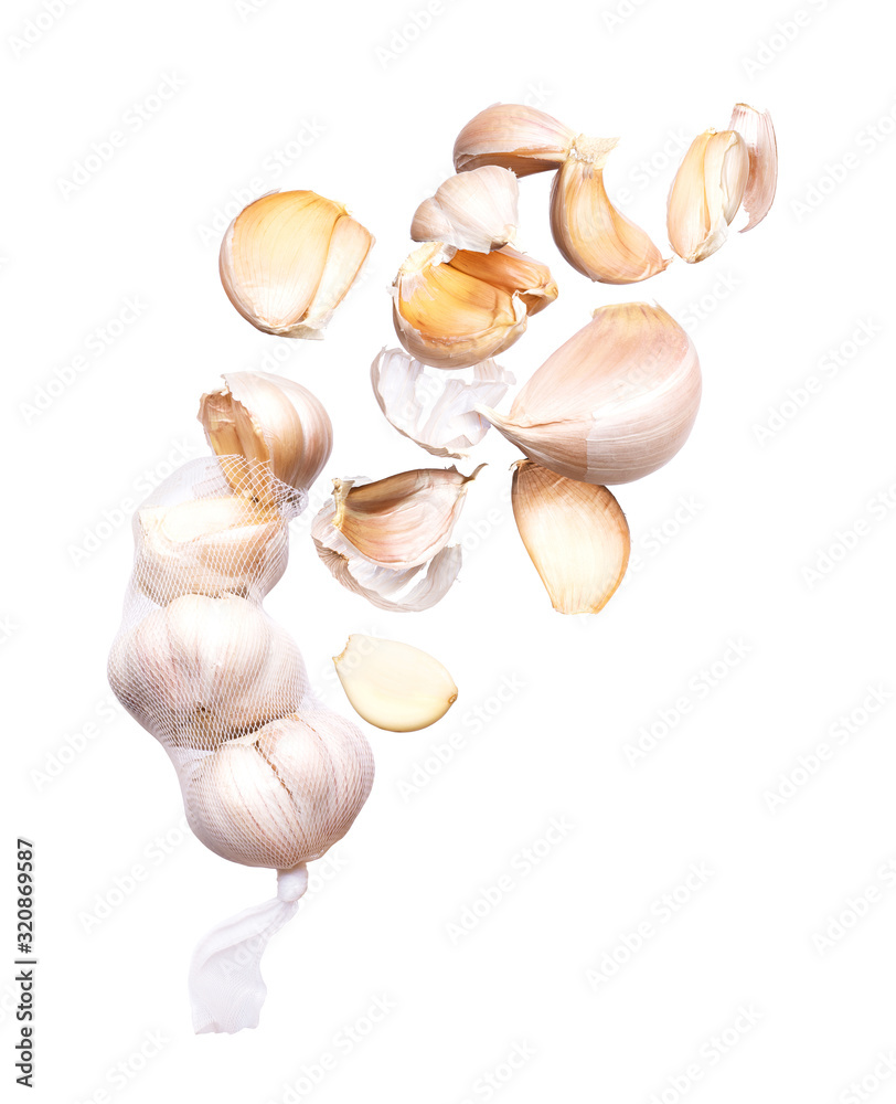 Cloves of garlic fly out of a mesh bag on a white background