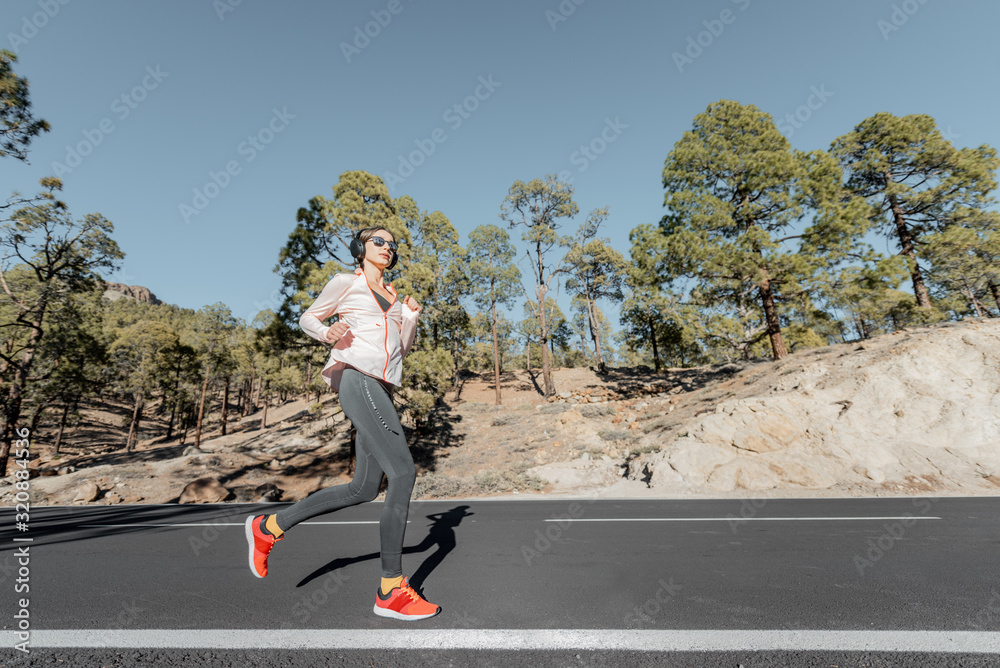 穿着运动服的年轻女子在森林中美丽的山路上慢跑，从s看风景开阔