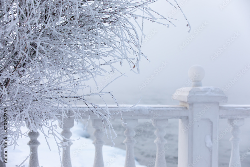 Frost and ice covered balusters on a lake shore in winter. Lake Baikal, Listvyanka, Siberia, Russia.