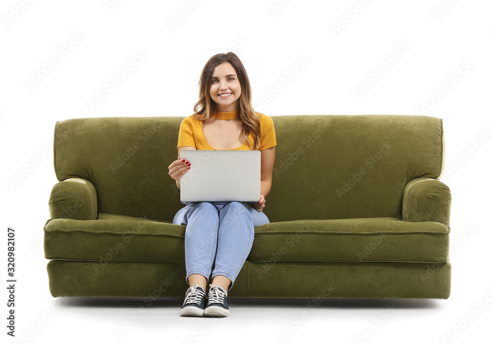 Young woman with laptop sitting on sofa against white background