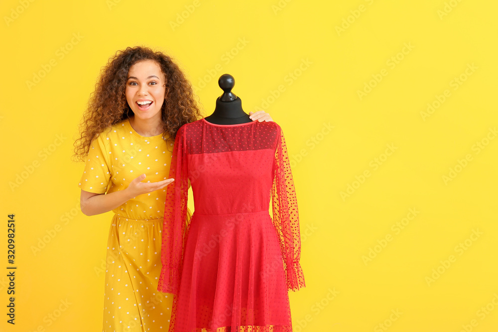 African-American stylist with mannequin on color background