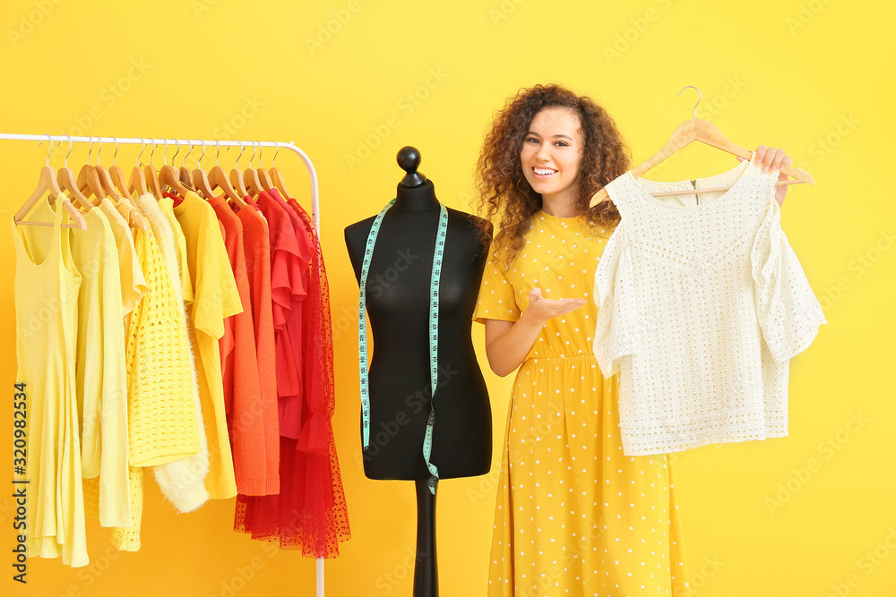 African-American stylist near mannequin and rack with modern clothes