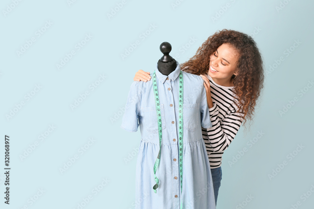 African-American stylist with mannequin on color background