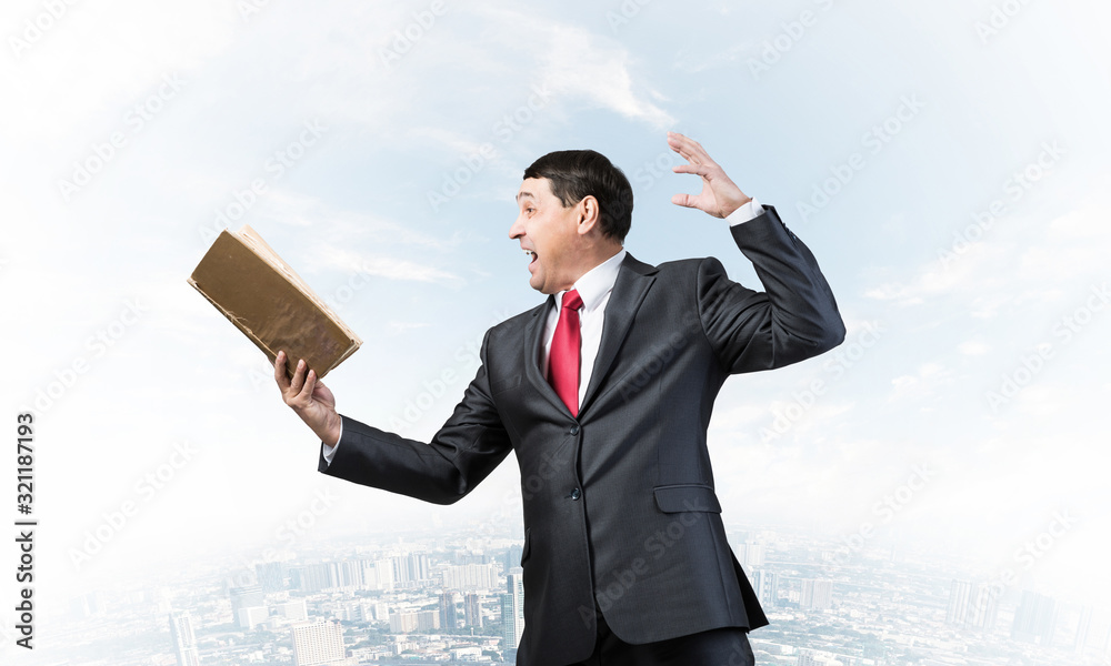 Expressive businessman looking in open book