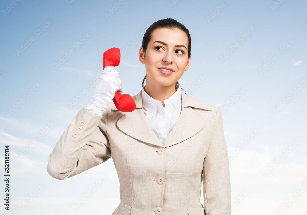 Attractive young woman holding red retro phone.