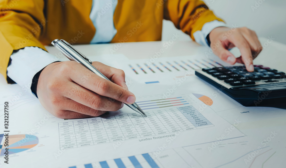 businesswoman working on desk using calculator and laptop analyzing finance