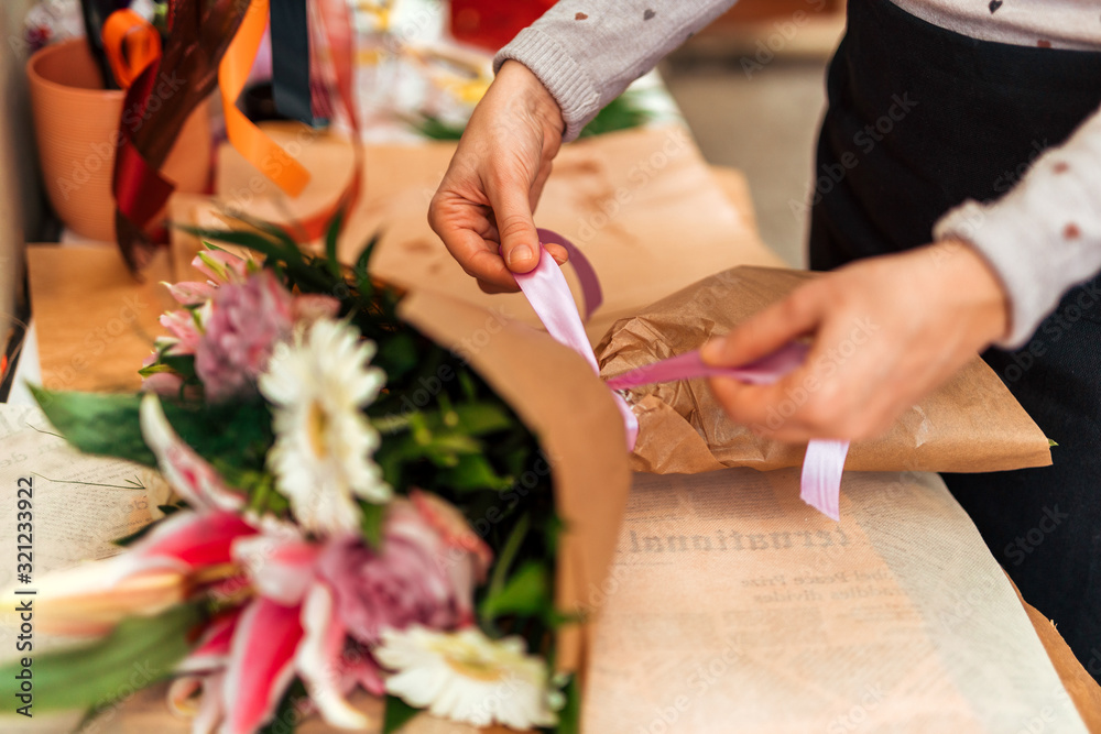 Florist finishing flower bouquet, tying ribbon.