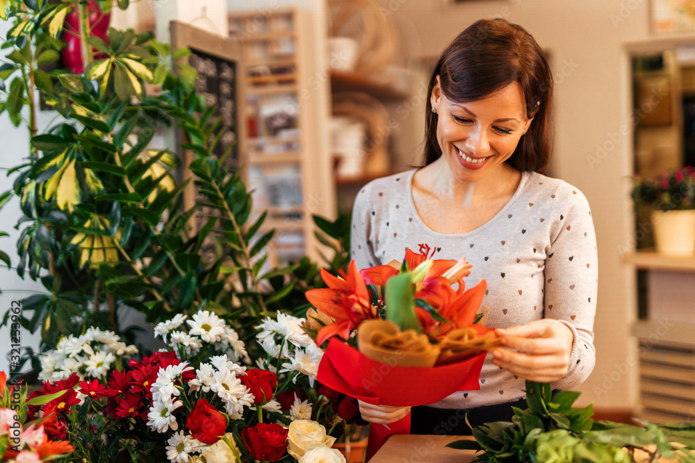 Happy small business owner, portrait. Positive florist holding beautifully decorated fresh flower bo