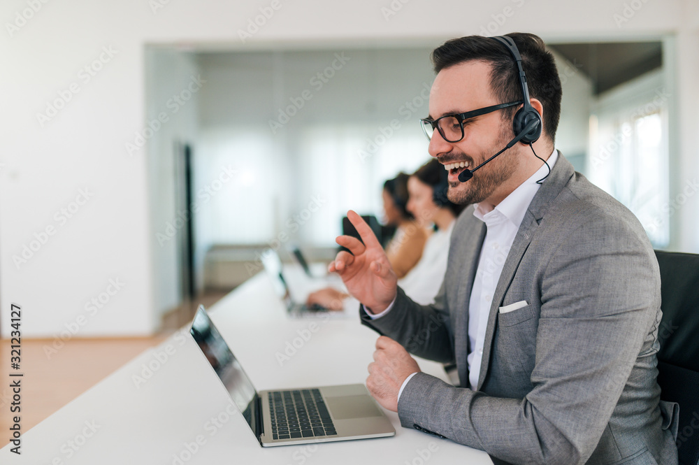 Smiling handsome customer support operator with headset working, talking with a client, portrait.