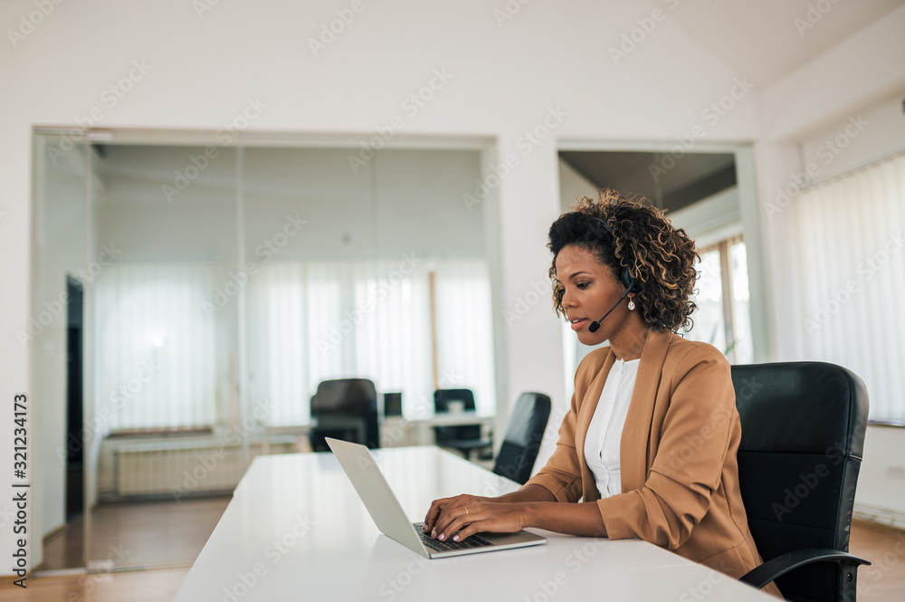 Charming young service desk consultant working on laptop, side view, copy space.