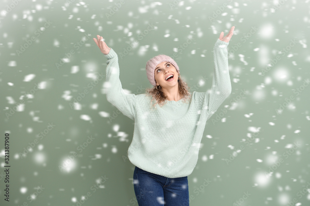 美丽的年轻女子穿着温暖的毛衣，背景是飘落的雪