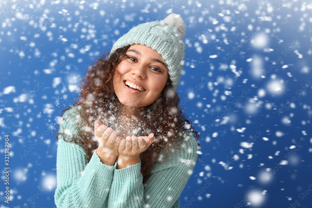 穿着保暖毛衣的年轻非裔美国妇女在彩色背景下玩雪